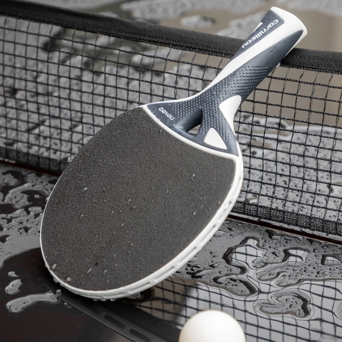 Raquette de ping-pong outdoor Nexeo 70 posée sur une table mouillée